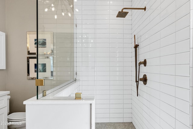 full bath featuring a tile shower, vanity, and toilet