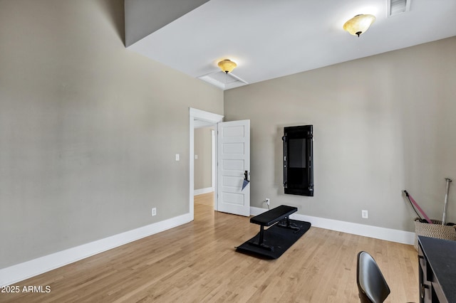 exercise room featuring baseboards, visible vents, and wood finished floors