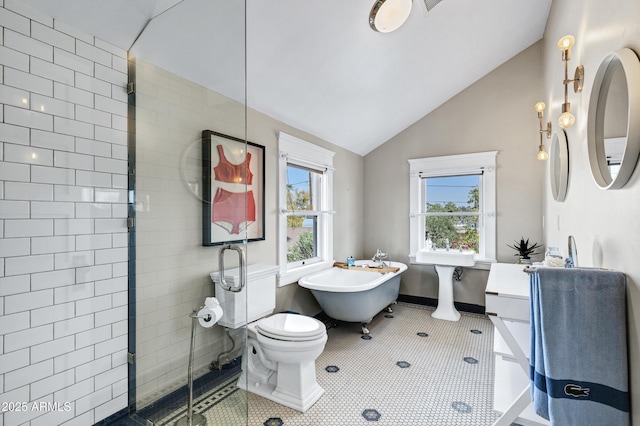 bathroom with lofted ceiling, a stall shower, a freestanding bath, and tile patterned floors