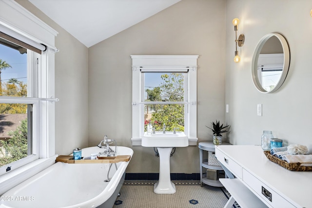 full bath featuring lofted ceiling, a freestanding tub, baseboards, and tile patterned floors