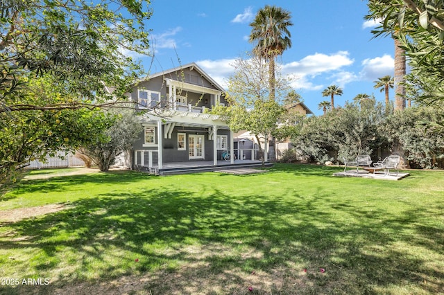 back of house featuring french doors, a lawn, a balcony, and fence