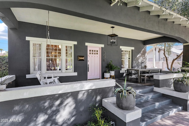 property entrance with covered porch and stucco siding