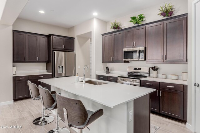 3852 E Bartlett Way, Chandler, AZ 85249 - kitchen with appliances with stainless steel finishes, a sink, a breakfast bar area, light wood finished floors, and dark brown cabinetry
