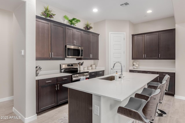 3852 E Bartlett Way, Chandler, AZ 85249 - kitchen featuring stainless steel appliances, a sink, light wood-style flooring, dark brown cabinets, and recessed lighting