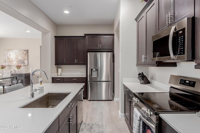 3852 E Bartlett Way, Chandler, AZ 85249 - kitchen featuring appliances with stainless steel finishes, a sink, dark brown cabinetry, light wood finished floors, and light countertops