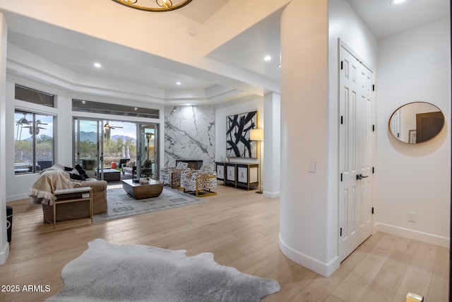 living room featuring a premium fireplace, light hardwood / wood-style flooring, and a tray ceiling