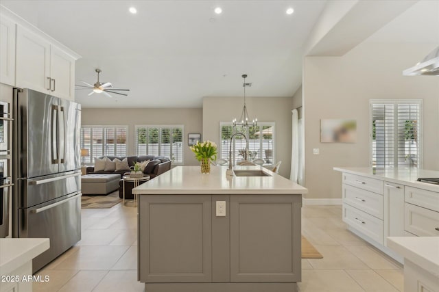 kitchen with light tile patterned floors, stainless steel appliances, a sink, white cabinetry, and light countertops