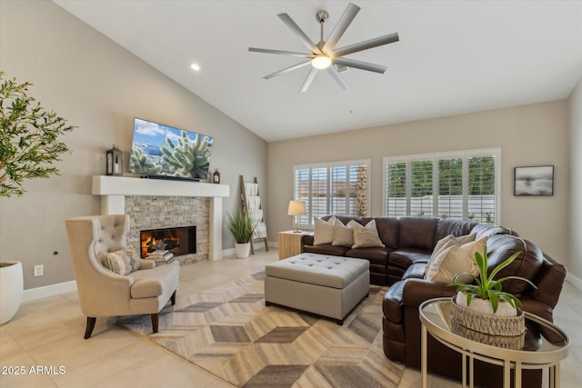 living room featuring ceiling fan, a stone fireplace, baseboards, and light tile patterned floors