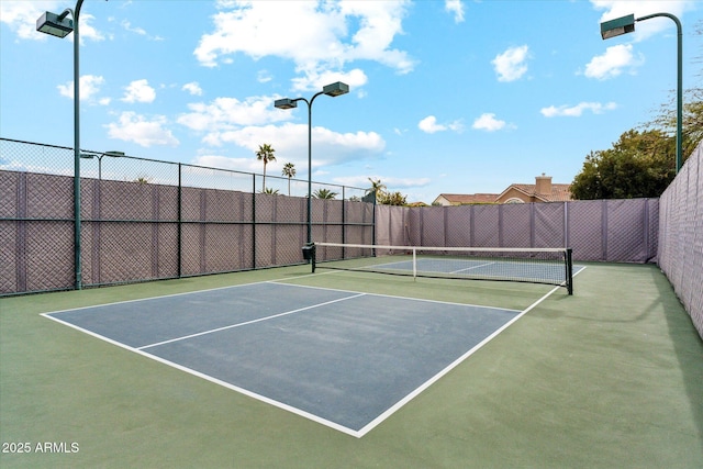 view of tennis court with community basketball court and fence