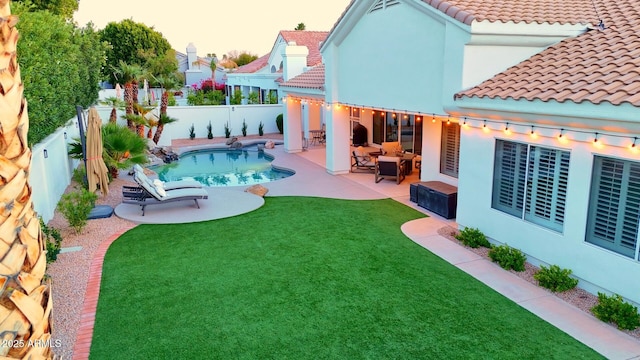 rear view of house with a fenced in pool, a tile roof, a yard, a patio area, and a fenced backyard