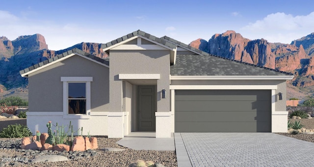 view of front of property with a mountain view, stucco siding, an attached garage, and decorative driveway