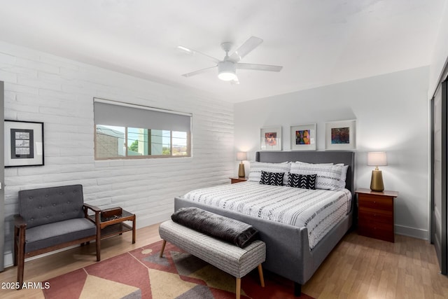 bedroom with brick wall, baseboards, ceiling fan, and wood finished floors