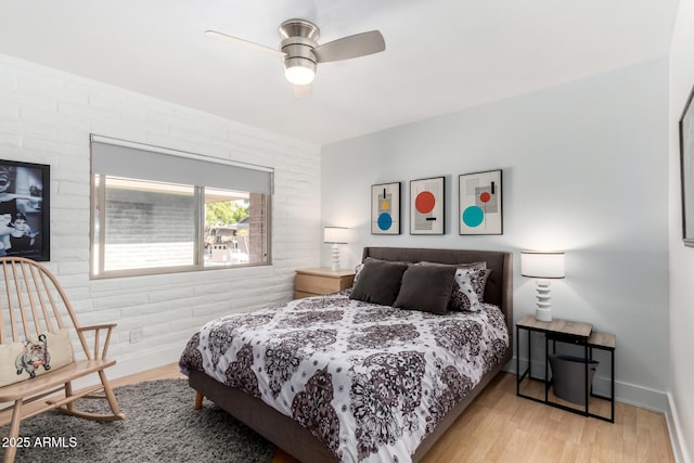 bedroom featuring brick wall, baseboards, and wood finished floors