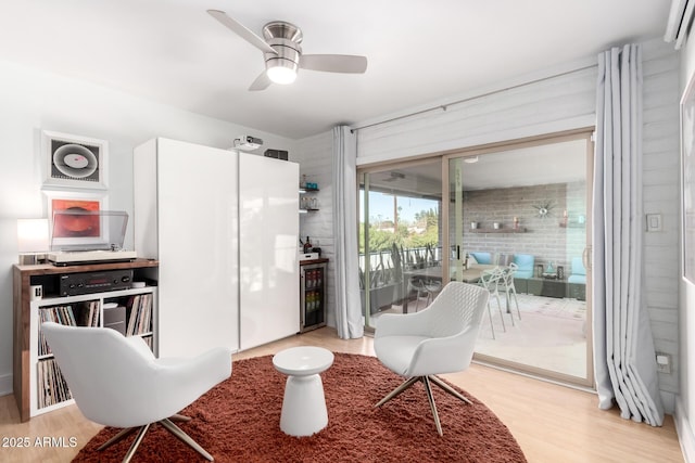 living area with ceiling fan, wine cooler, and light wood-type flooring