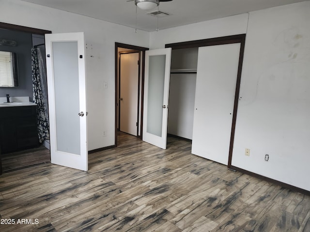 unfurnished bedroom featuring french doors, baseboards, wood finished floors, and visible vents