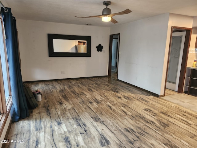 unfurnished room with ceiling fan, wood finished floors, and baseboards