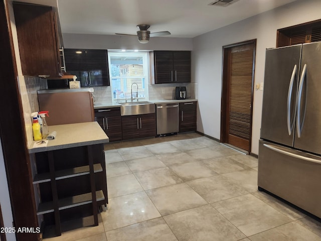 kitchen with tasteful backsplash, a ceiling fan, appliances with stainless steel finishes, light countertops, and a sink