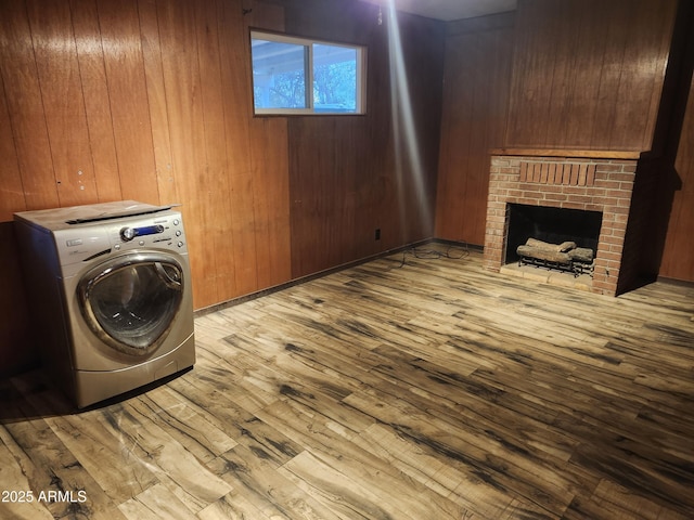clothes washing area featuring laundry area, wood finished floors, wooden walls, and washer / dryer