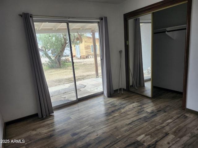 unfurnished bedroom with access to outside, baseboards, and dark wood-style floors