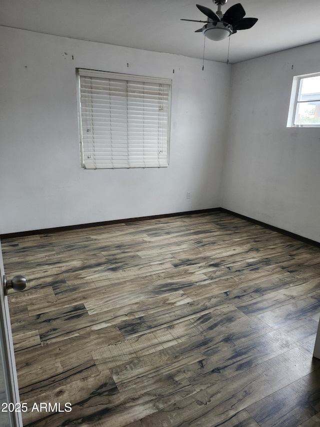 spare room featuring baseboards, wood finished floors, and ceiling fan