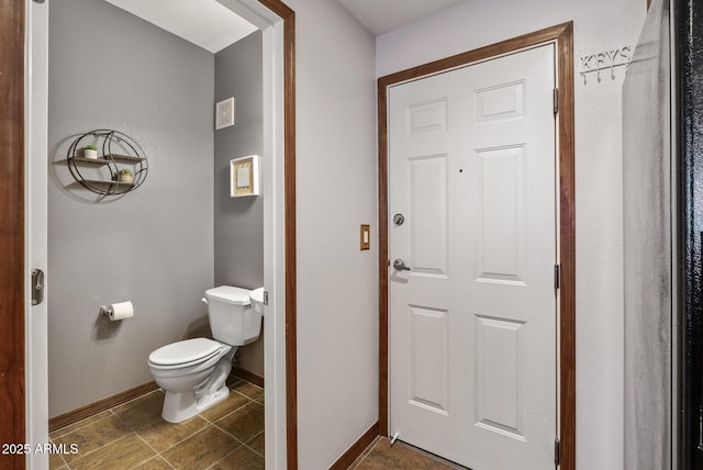 bathroom with toilet, baseboards, and tile patterned flooring