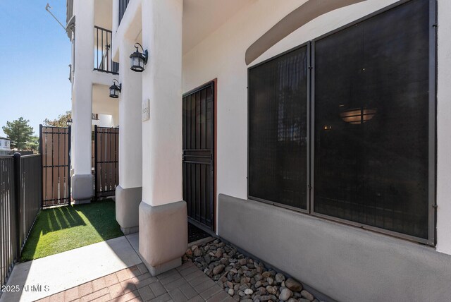 view of exterior entry featuring fence and stucco siding