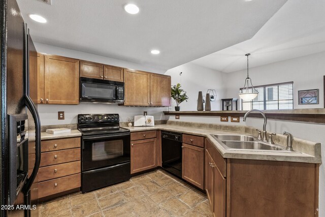 kitchen featuring black appliances, a sink, a peninsula, light countertops, and hanging light fixtures