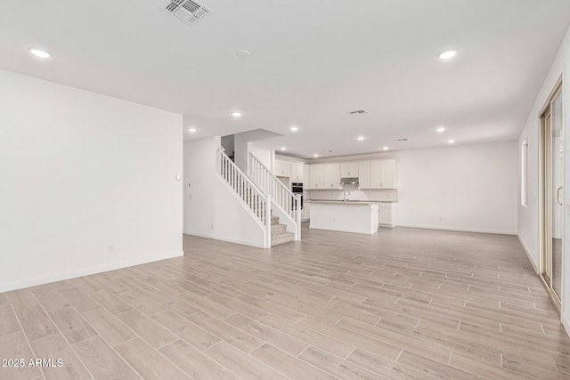 unfurnished living room featuring light hardwood / wood-style floors and sink