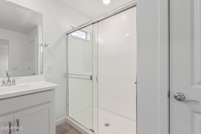 bathroom featuring vanity, a shower with door, and wood-type flooring