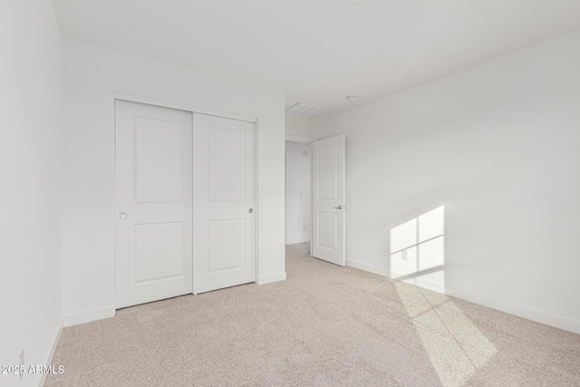 unfurnished bedroom featuring light colored carpet and a closet