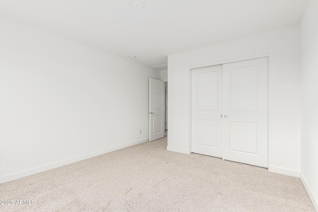 unfurnished bedroom featuring light colored carpet and a closet