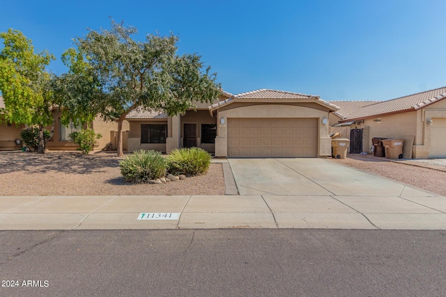 view of front facade with a garage, a tile roof, driveway, and stucco siding