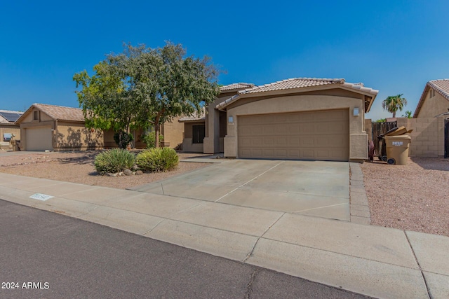 single story home with an attached garage, a tiled roof, concrete driveway, and stucco siding