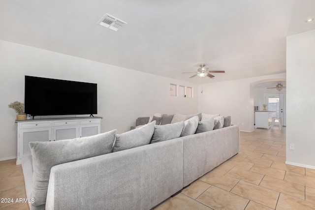 living room featuring ceiling fan, arched walkways, visible vents, and baseboards