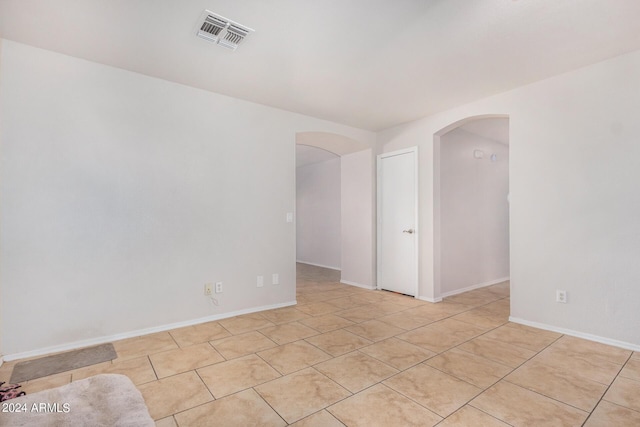 unfurnished room featuring baseboards, visible vents, and arched walkways