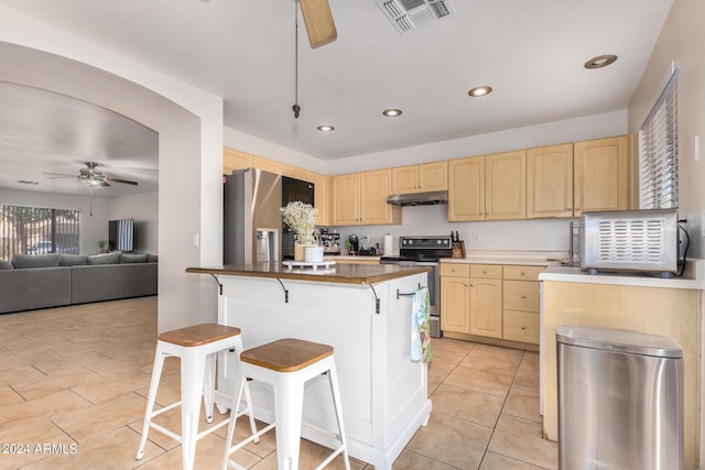 kitchen with visible vents, appliances with stainless steel finishes, light brown cabinets, ceiling fan, and a kitchen bar