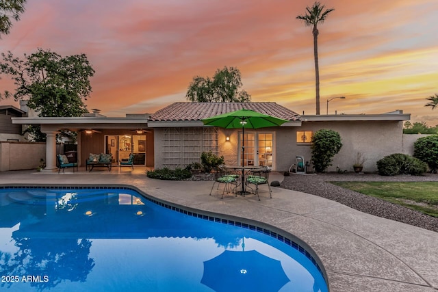 8219 E Morgan Trl, Scottsdale, AZ 85258 - pool at dusk featuring a patio, french doors, an outdoor pool, and a ceiling fan