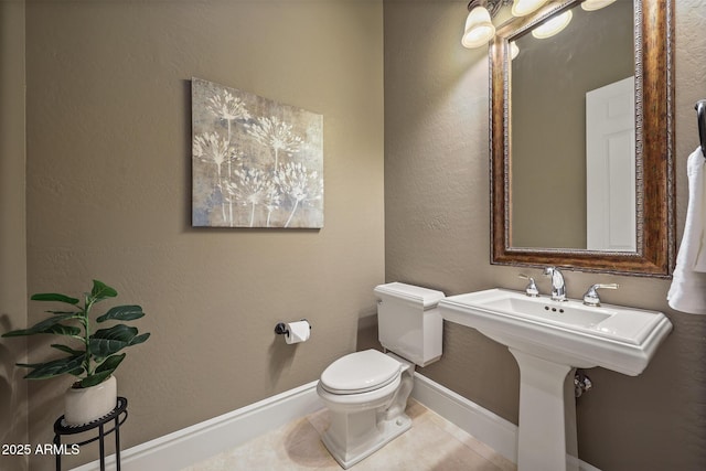 half bathroom with baseboards, a textured wall, toilet, and tile patterned floors