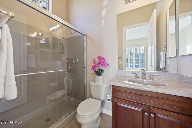 bathroom with a stall shower, vanity, toilet, and tile patterned floors