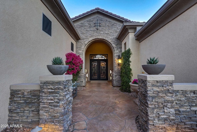 view of exterior entry with stone siding and stucco siding