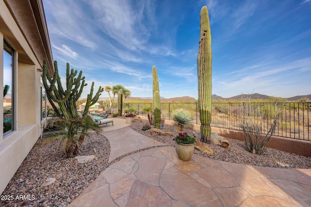 view of patio / terrace with fence and a mountain view