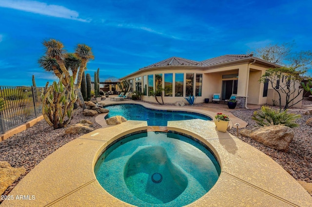 back of house featuring fence, a pool with connected hot tub, a tiled roof, stucco siding, and a patio area