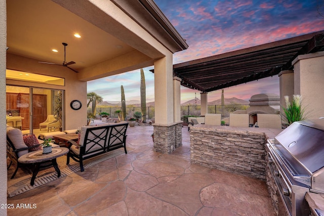 patio terrace at dusk with fence and an outdoor kitchen