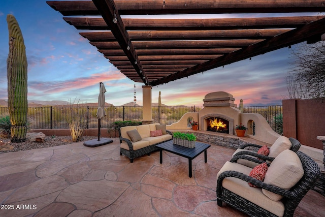 patio terrace at dusk with an outdoor living space with a fireplace, fence private yard, and a pergola