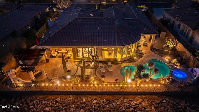 back of house at twilight with a patio area, a fenced backyard, an outdoor pool, and a tiled roof