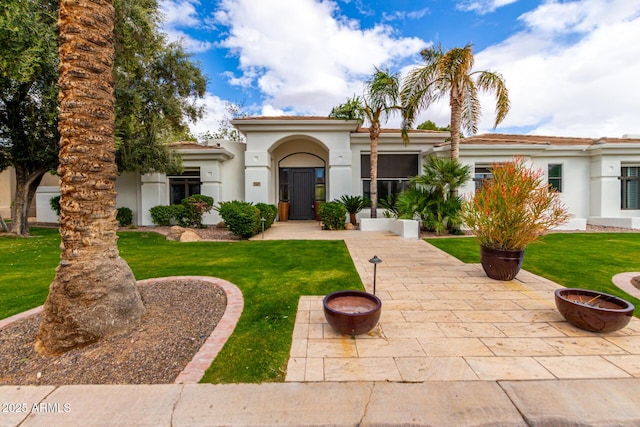 mediterranean / spanish-style house with stucco siding, a patio, a fire pit, and a front lawn