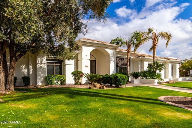 mediterranean / spanish-style house featuring stucco siding, a tiled roof, and a front lawn