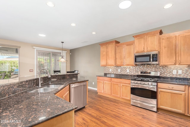 kitchen with a sink, tasteful backsplash, recessed lighting, light wood-style floors, and appliances with stainless steel finishes