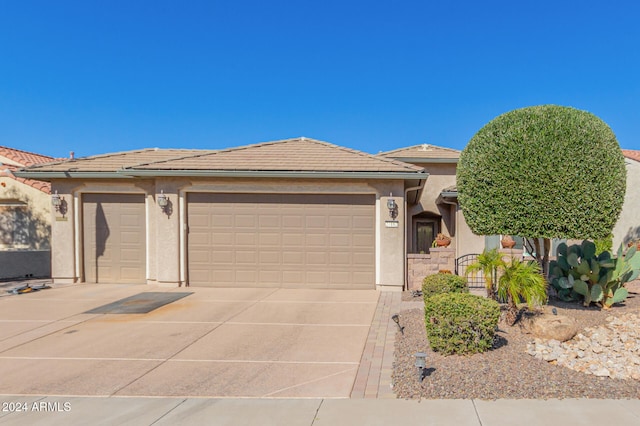 ranch-style house featuring concrete driveway, a tiled roof, a garage, and stucco siding