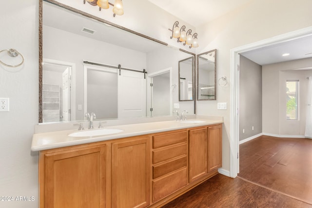 bathroom with a sink, visible vents, baseboards, and wood finished floors